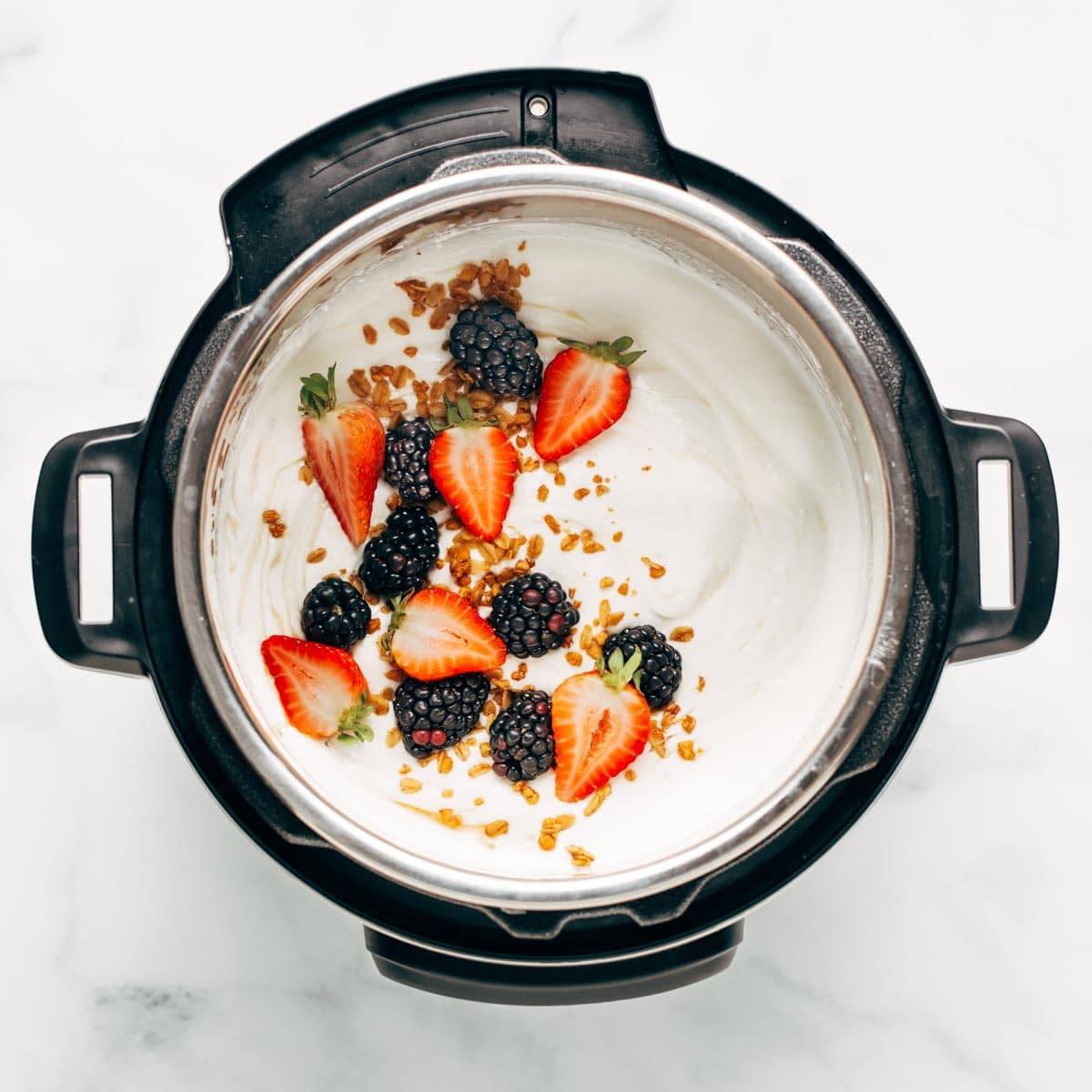 Cooked yogurt in the Instant Pot. The yogurt has berries and granola sprinkled on top.