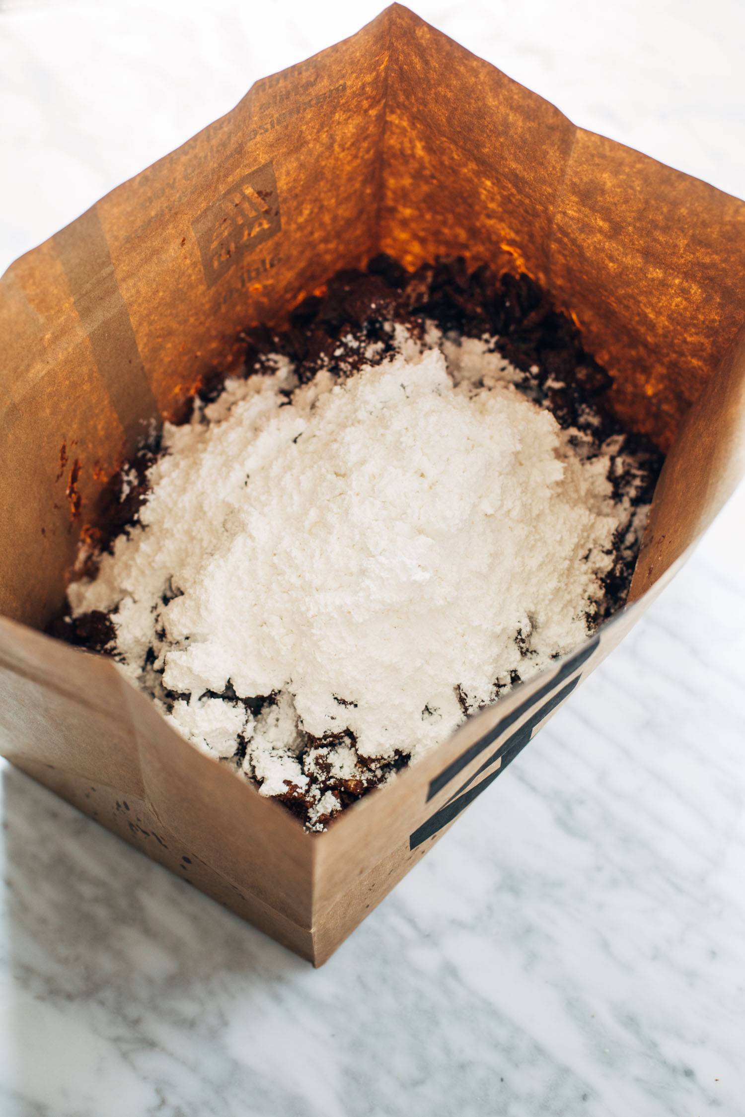 Chocolate chex mix and powdered sugar in a bowl.