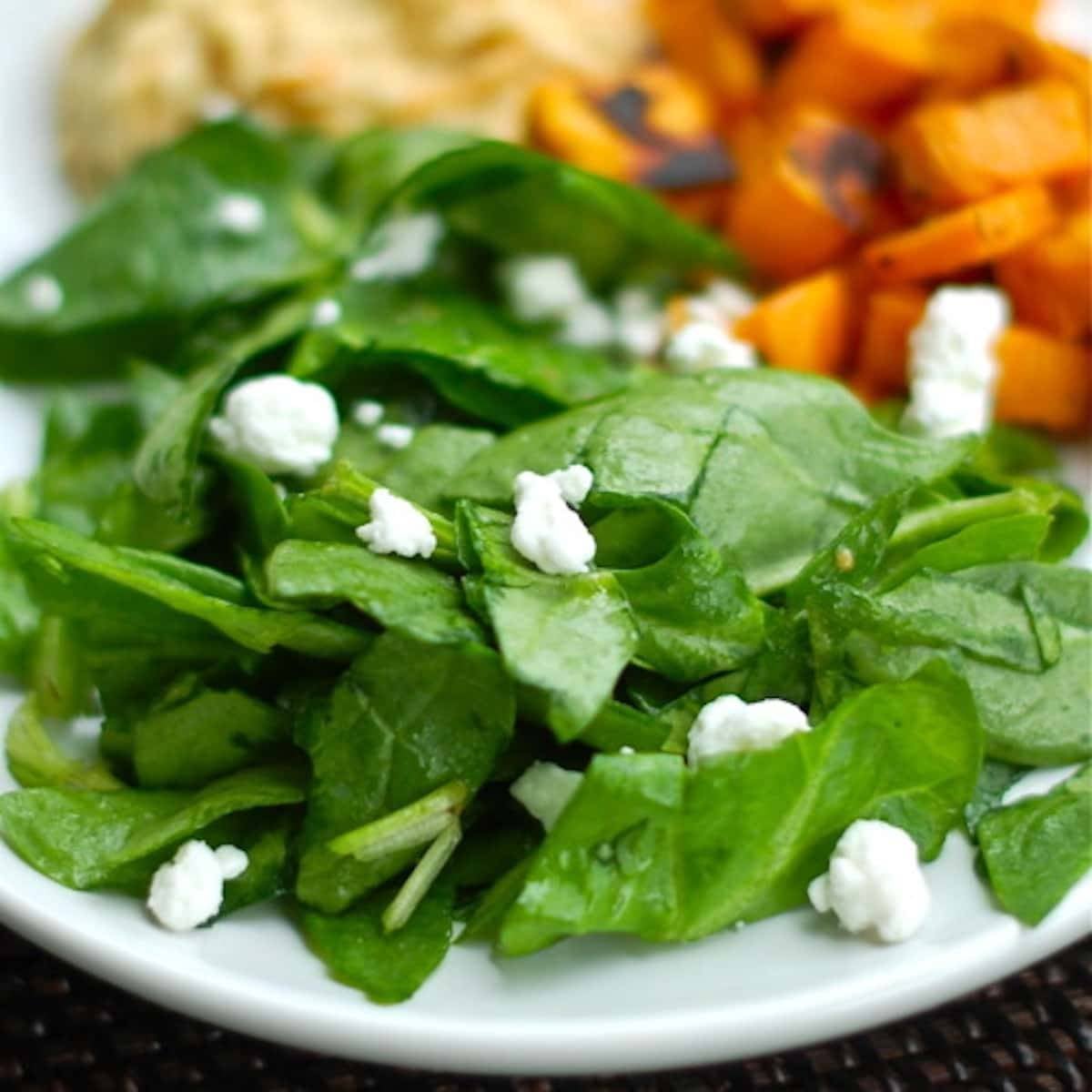 Roasted sweet potatoes with a side of hummus and a spinach salad.