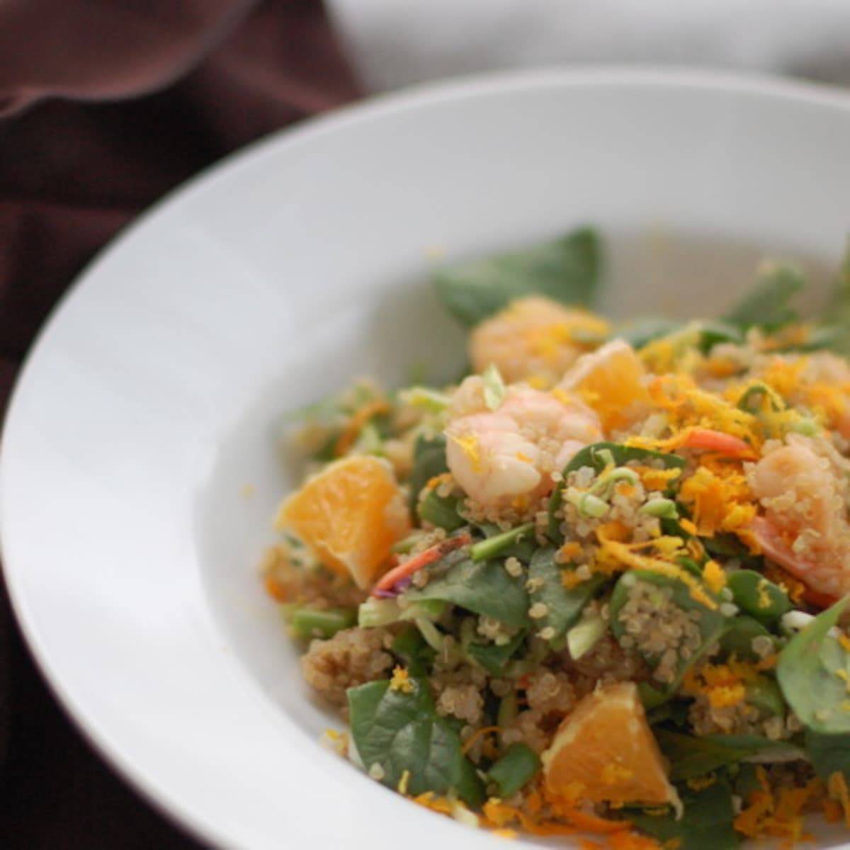 Shrimp and quinoa salad in a bowl with toppings.