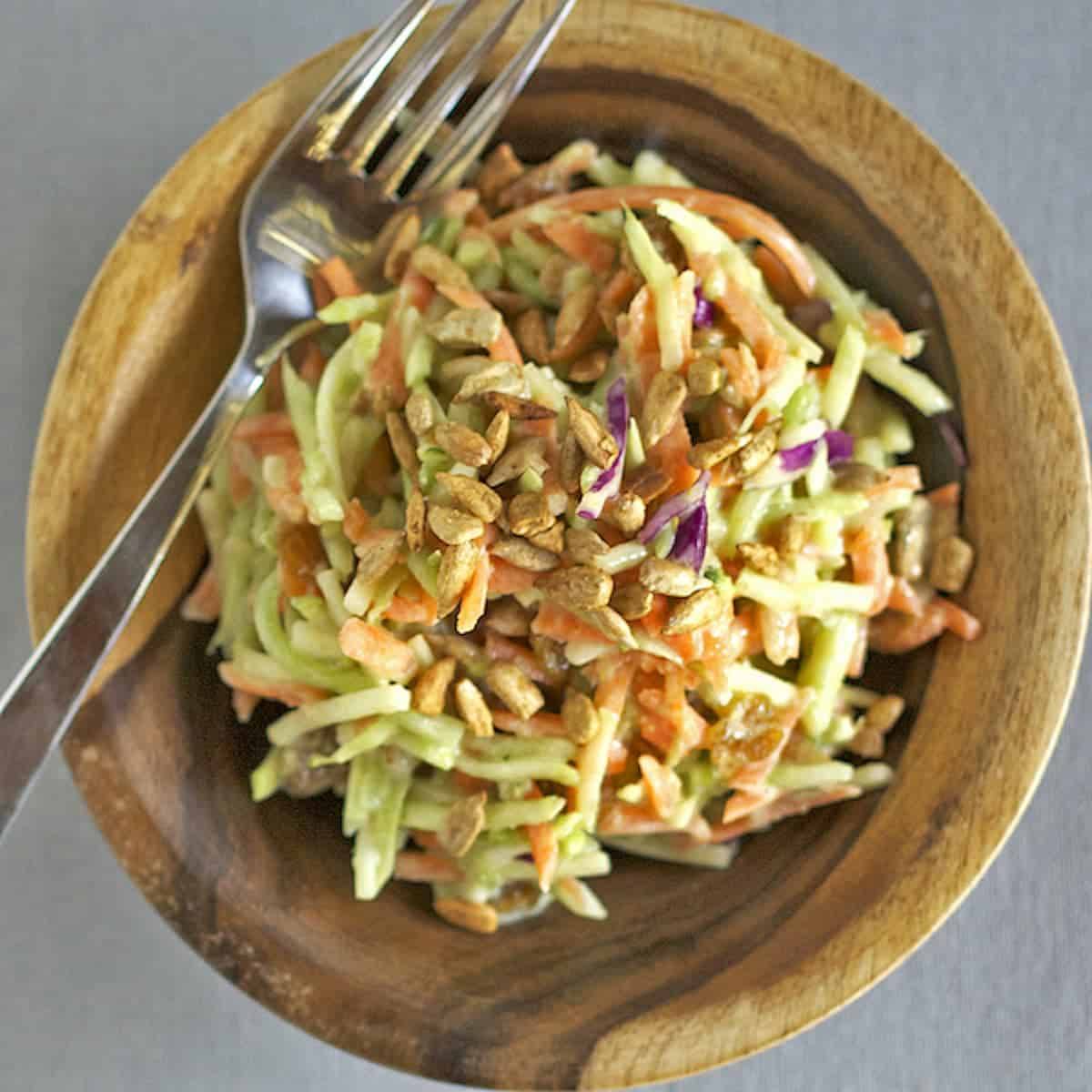 Green curry salad in a wooden bowl with a fork.